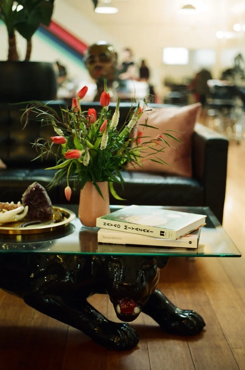 Pony Studios indoor lounge with a black panther coffee table, fresh tulips, and a leather couch