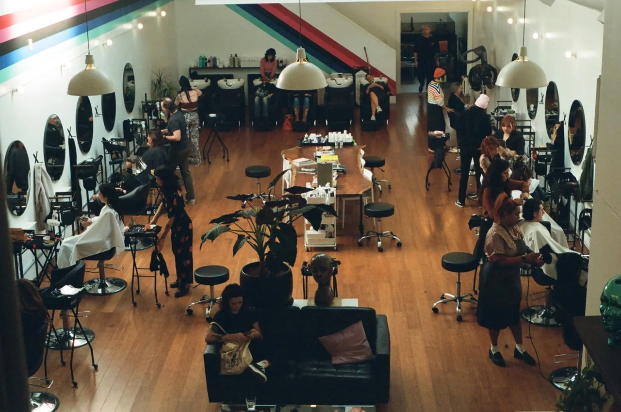 Aerial view of Pony Studios salon floor with stylists at work, lounge seating, and the rainbow stripe across the ceiling